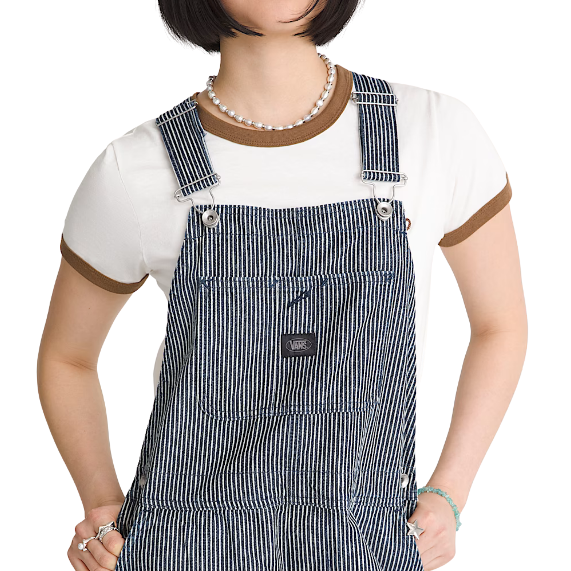 A woman modeling gray and white vans chore stripe vertically striped work overalls over a white t-shirt, standing against a plain white background.