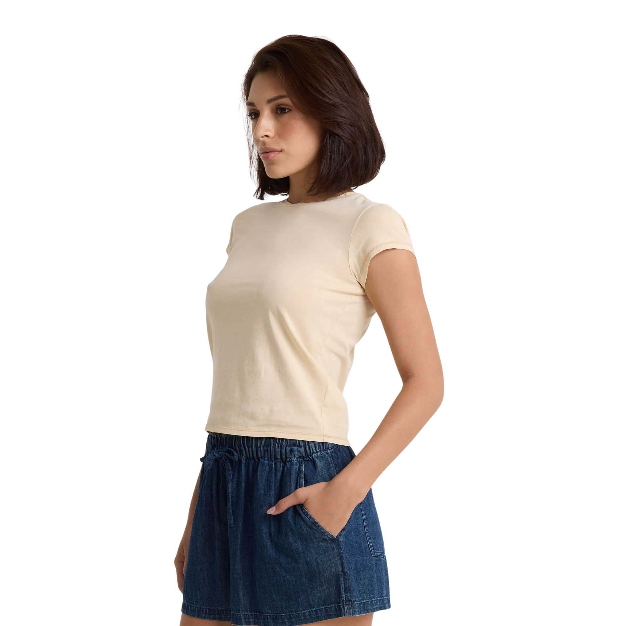 Woman wearing a beige volcom lived in stone wash t-shirt and blue shorts on a white background
