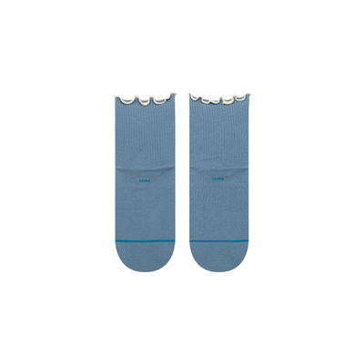 A pair of stance light blue ankle socks with scalloped ruffle edges at the top and a small white circular logo on the side, displayed against a plain white background.
