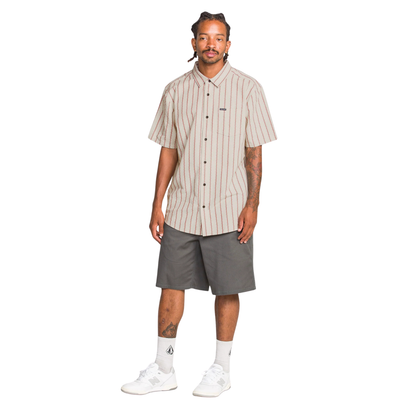 Man wearing a beige and red striped volcom sato stripe short sleeve shirt on a white background
