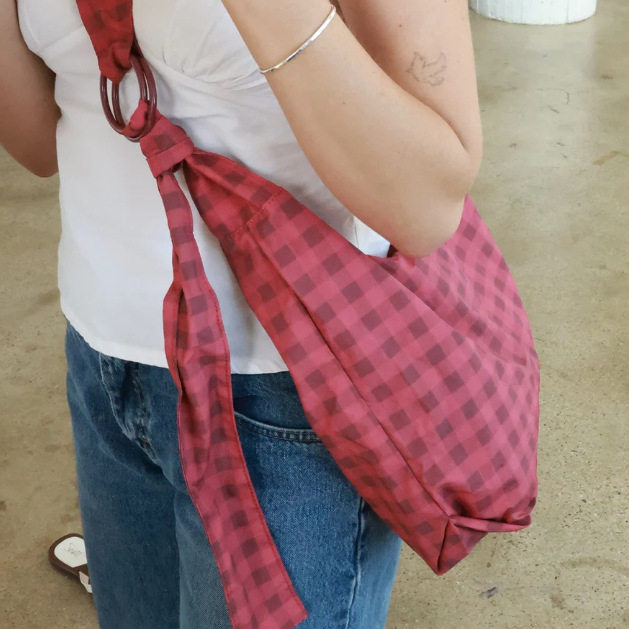 a woman wearing a two tone red gingham thread small slouchy shoulder bag