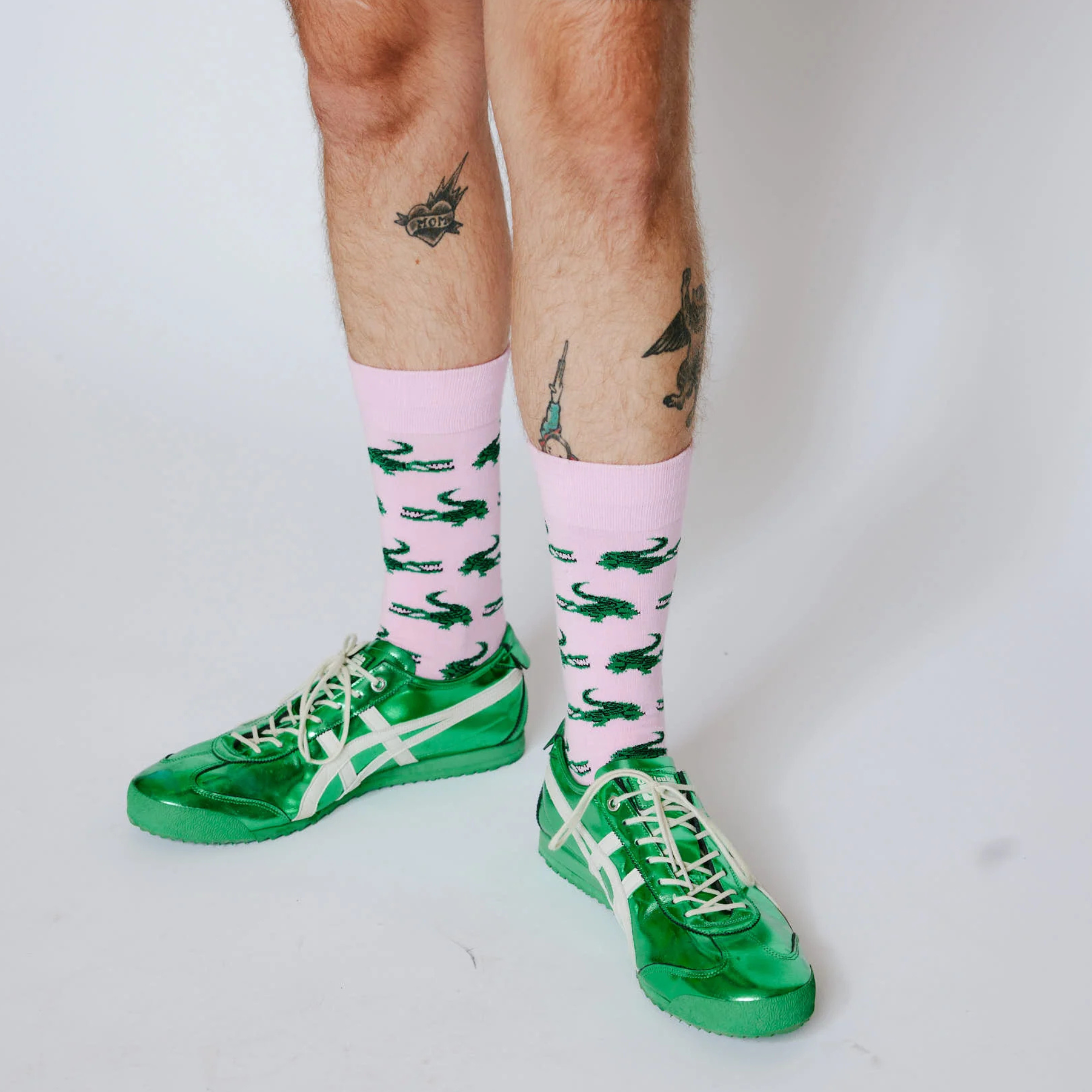 Pink bonfolk socks with green alligator pattern on a white background