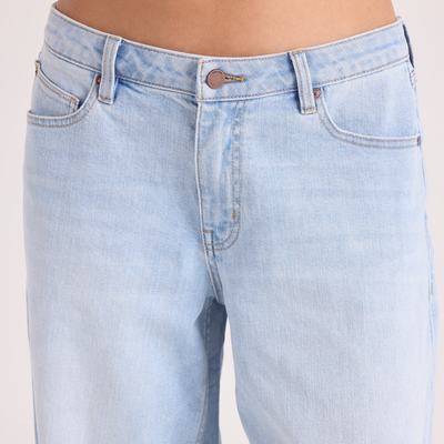 A woman in a black hat and black tee shirt wearing volcom stoned boyfriend low rise jeans on a white background
