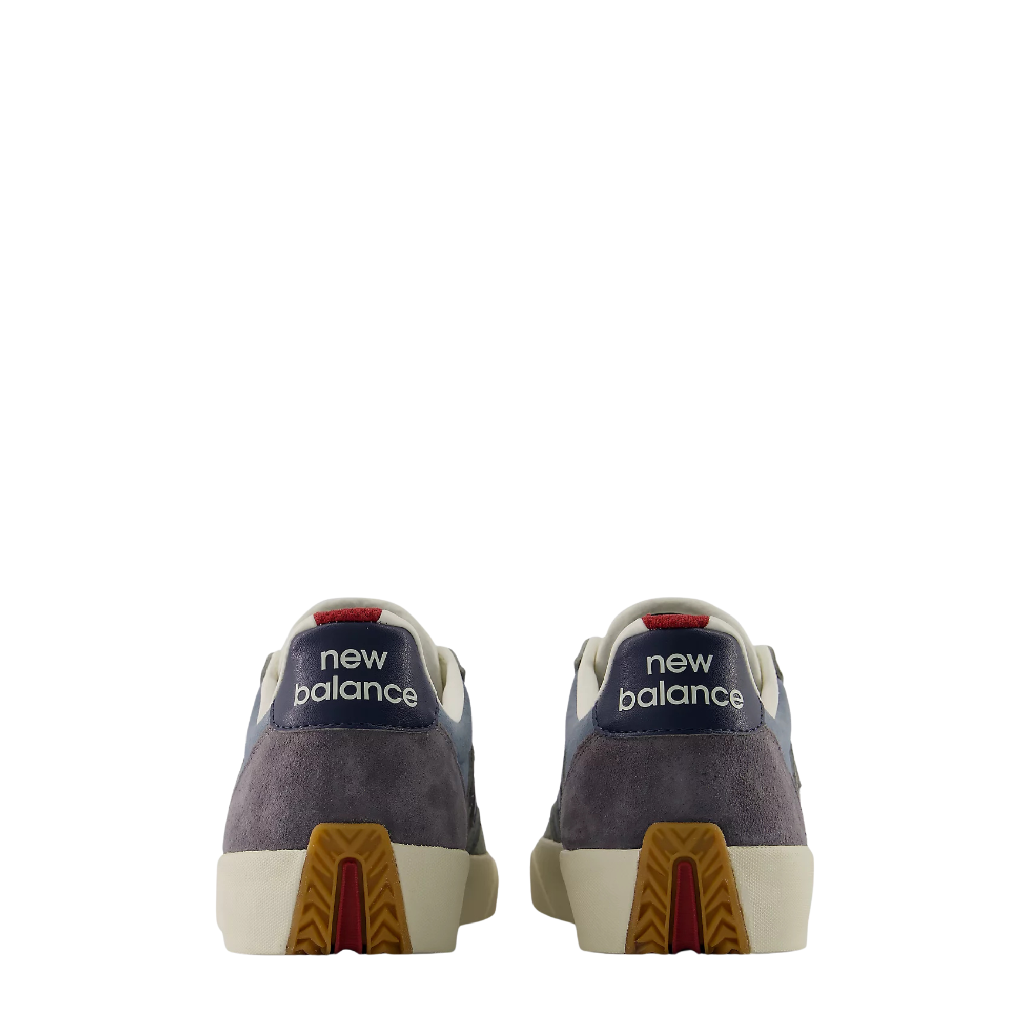 A pair of New Balance low-top sneakers shown from the back, featuring navy blue suede and leather panels, off-white leather overlays, a cream midsole, and a brown and red geometric outsole.