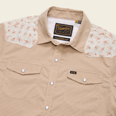 close up of A beige and brown checkered long-sleeve howler h bar tech western shirt with beige floral patterned yoke panels on the shoulders, featuring two buttoned chest pockets and a button-down front.