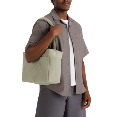 Man holding a beige shoulder bag against a white background