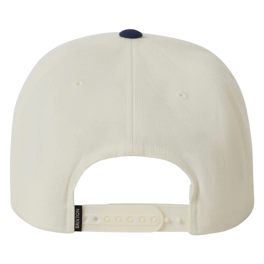 Beige and navy brixton snapback cap with a logo on a white background