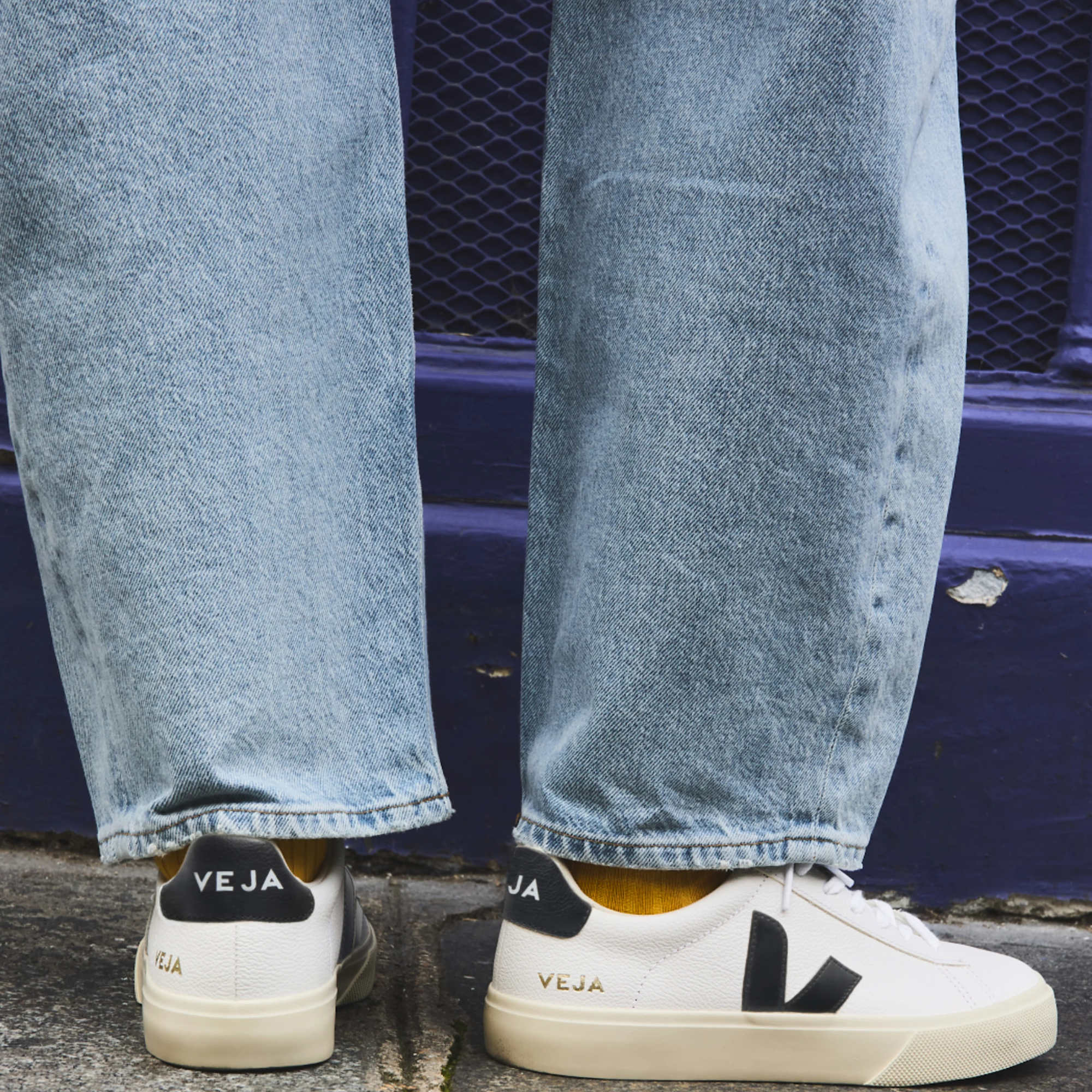 persone wearing wide leg jeans with a pair of white veja campo leather shoes with black V and off white sole