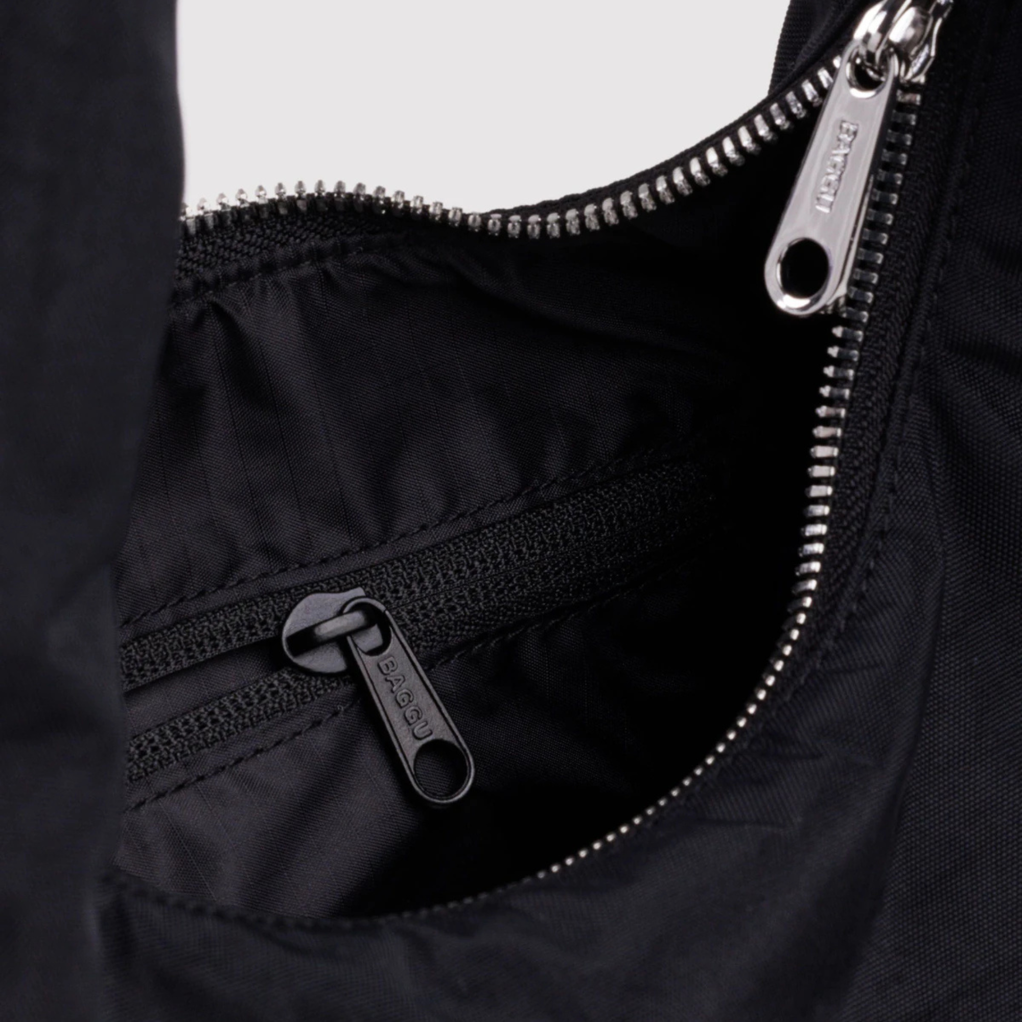 Close-up of a black slouchy baggu nylon meringue shoulder bag with a single strap, photographed against a solid white background.