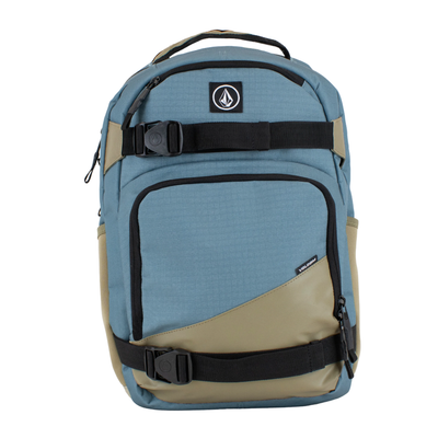 A Volcom grindstone skateboard backpack in slate blue and tan with black straps and zippers, shown against a plain white background.