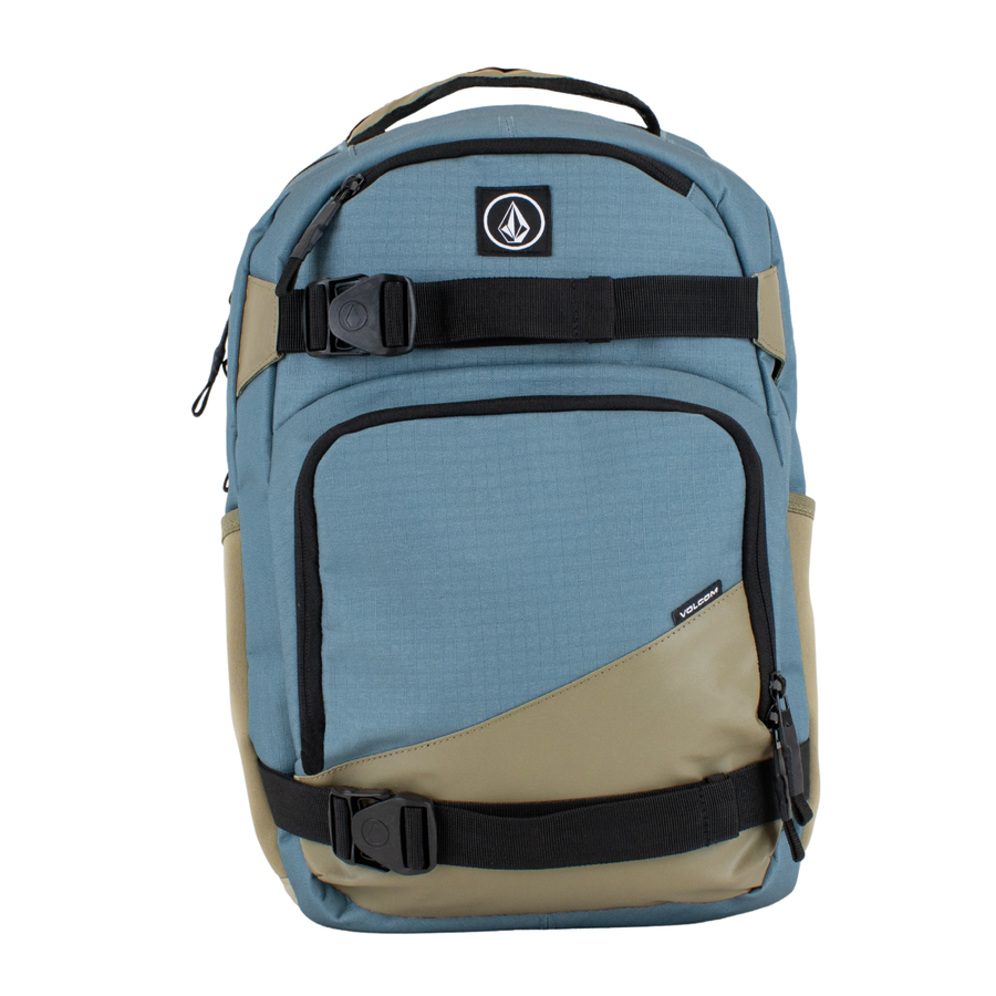 A Volcom grindstone skateboard backpack in slate blue and tan with black straps and zippers, shown against a plain white background.