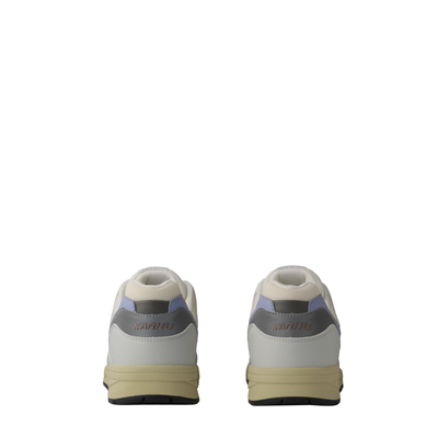 A low-top Legacy 96 sneaker by KARHU in light gray and off-white, featuring a lavender purple heel accent, dark gray side stripes, and a beige midsole.