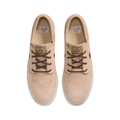 A Nike sb janoski low-top sneaker in a light beige suede and canvas mix, featuring a dark brown Swoosh logo, matching brown laces, and a thick white rubber sole.