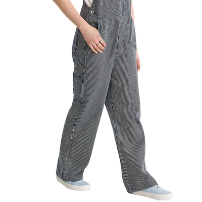 A woman modeling gray and white vans chore stripe vertically striped work overalls over a white t-shirt, standing against a plain white background.