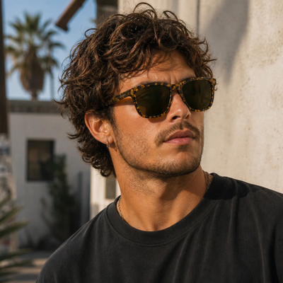 Man wearing glassy deric premium polarized Sunglasses with yellow and black tortoiseshell frame and a black shirt with a blurred background