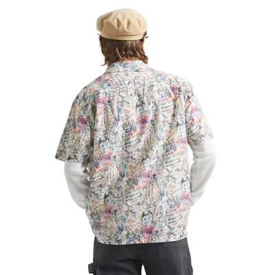 man wearing a brixton cru short sleeve woven shirt with graffiti pattern on a white background