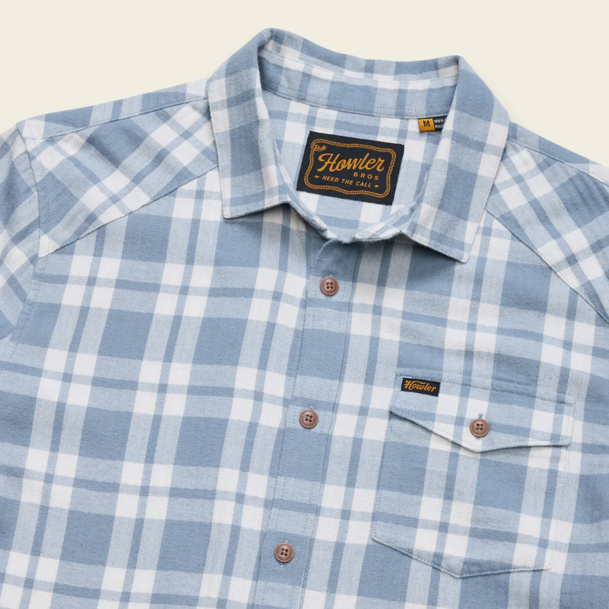A light blue and white plaid howler brothers la grange lightweight flannel long-sleeve button-up shirt with brown buttons, a chest pocket, and a visible brand label on the collar and chest pocket.