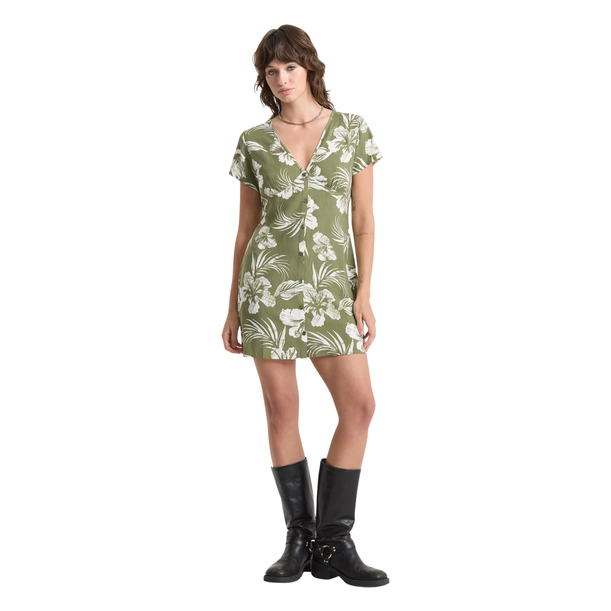 Woman wearing a green volcom vroom service dress with white floral pattern on a white background