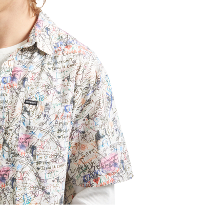 man wearing a brixton cru short sleeve woven shirt with graffiti pattern on a white background