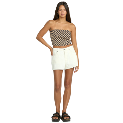 Woman wearing a checkered strapless top and white volcom straight up shorts on a white background