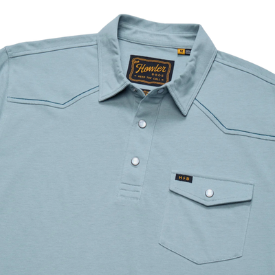 close up of A light blue short-sleeve Howler brothers ranchero polo shirt with western-style stitching, a two-button placket, and a chest pocket