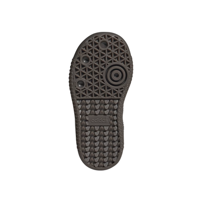 bottom view of A single Adidas Samba kids sneaker in black leather with signature white side stripes, a gold 'SAMBA' text on the side, and a dark brown gum sole, shown against a plain white background.