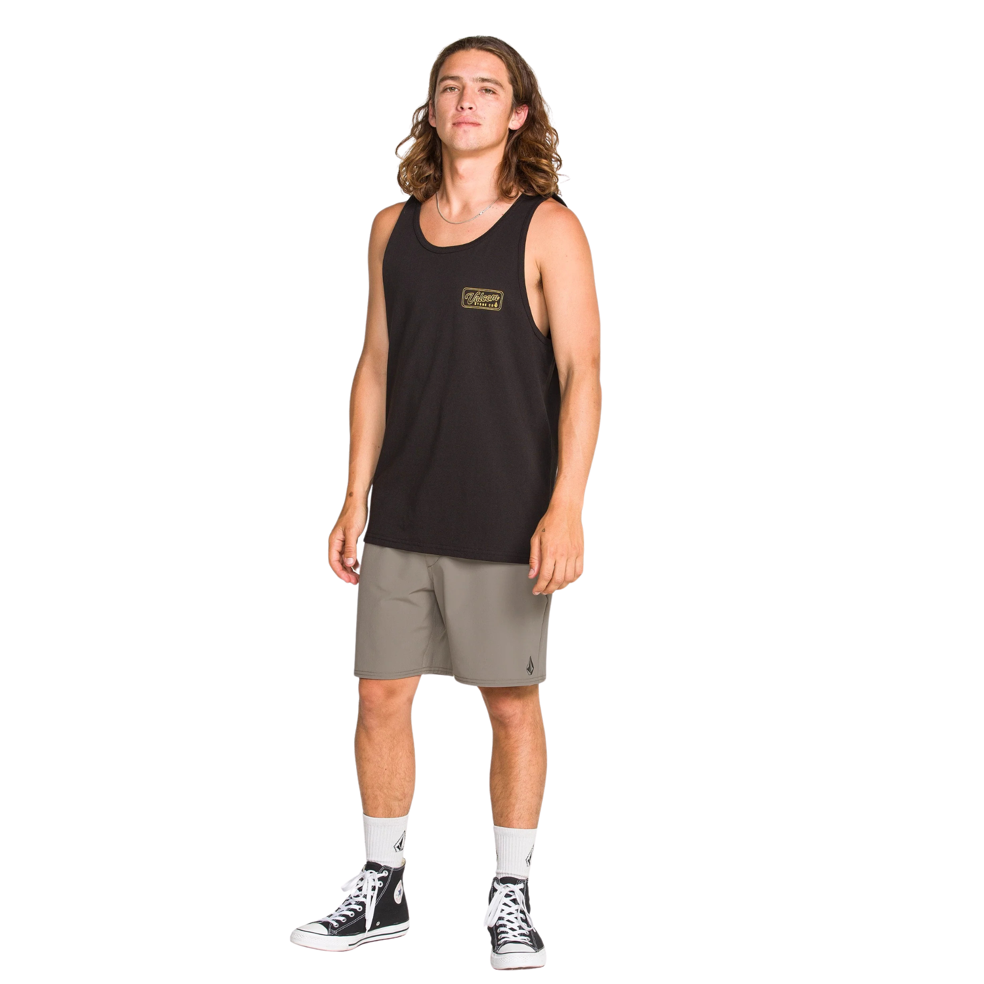 Man wearing a black tank top and TAN volcom nomaly elastic waist shorts on a white background