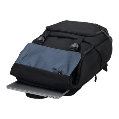 A black and slate blue backpack with a laptop insert, shown on a plain white background. The brand name 'volcom' is visible on the blue front pocket.