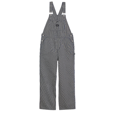 A woman modeling gray and white vans chore stripe vertically striped work overalls over a white t-shirt, standing against a plain white background.