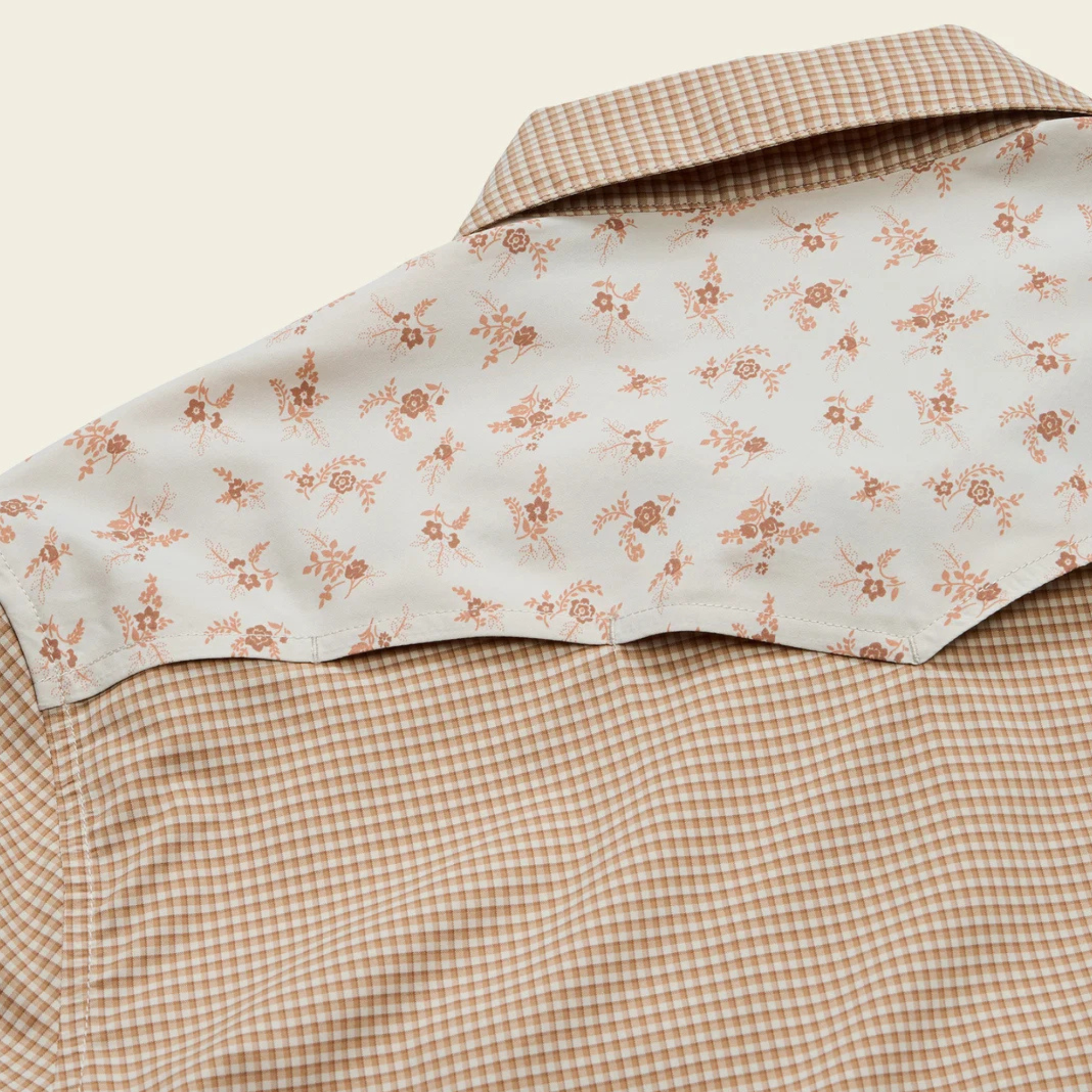 close up of the back of A beige and brown checkered long-sleeve howler h bar tech western shirt with beige floral patterned yoke panels on the shoulders, featuring two buttoned chest pockets and a button-down front.