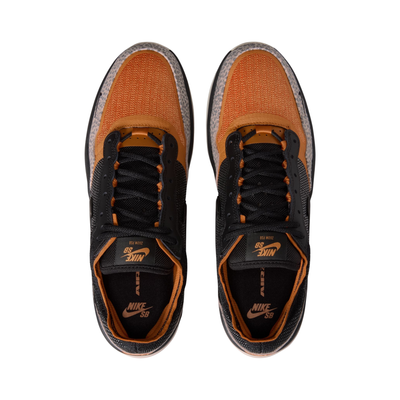 A Nike SB PS8 skateboard sneaker in black, orange, and gray leopard print, from a top-down view. The shoes feature a black mesh and synthetic upper with vibrant orange overlays, black laces, and orange accents inside the collar and on the tongue.