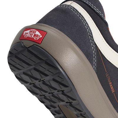 close up of a A low-top vans ultrarange se 2.0 sneaker against a solid white background. The shoe features a dark gray upper with a prominent off-white side stripe, a dark gray sole, and subtle orange-red accents on the collar lining and side details.