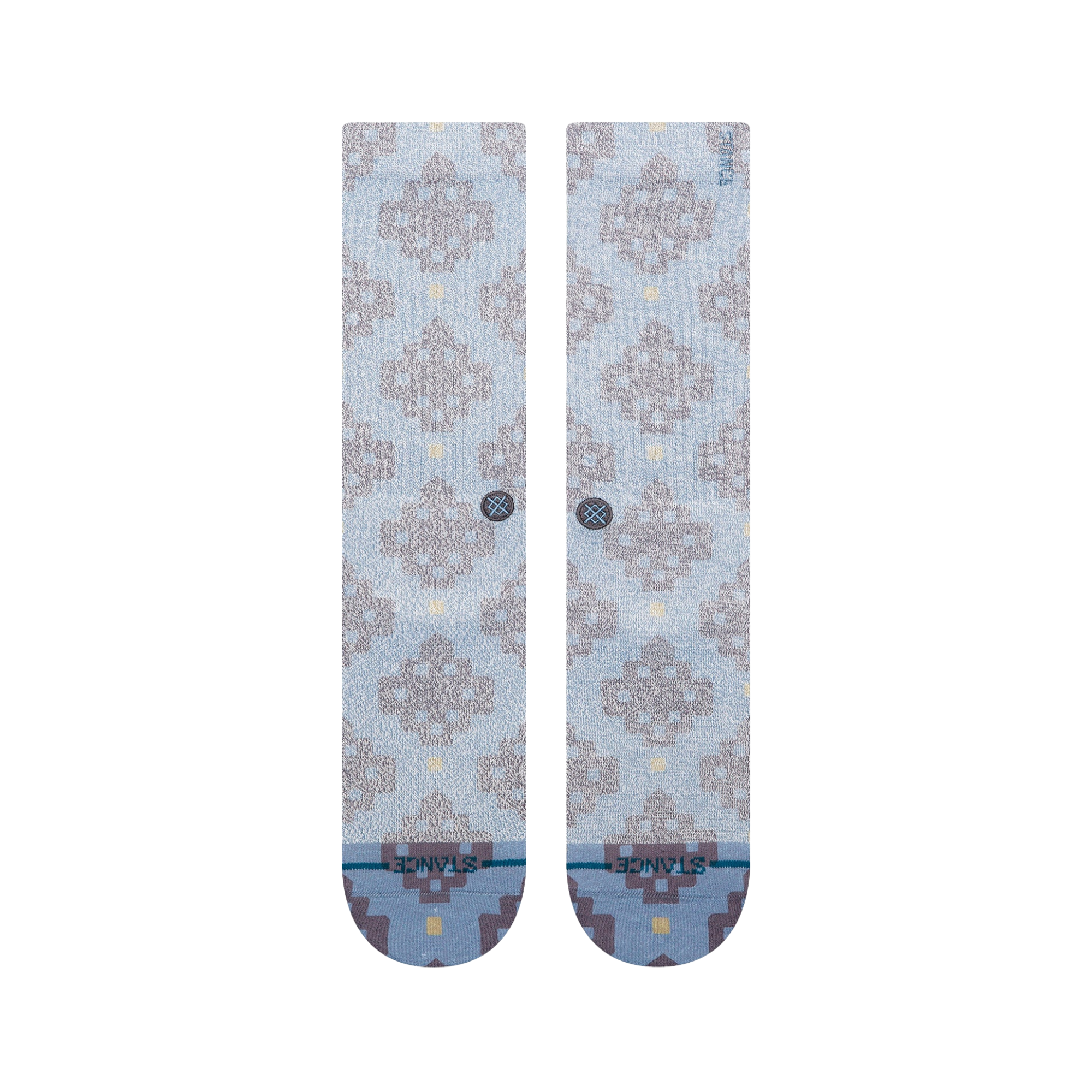 A pair of Stance alhambra butterblend crew socks in a light blue-gray colorway with a distressed brown tree pattern and small yellow accents, shown on a plain white background.