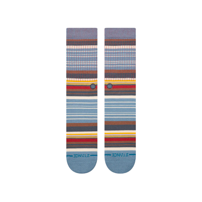 A pair of stance jorongo pop crew socks with a multicolor striped pattern featuring shades of blue, brown, red, yellow, and white, displayed against a plain white background.