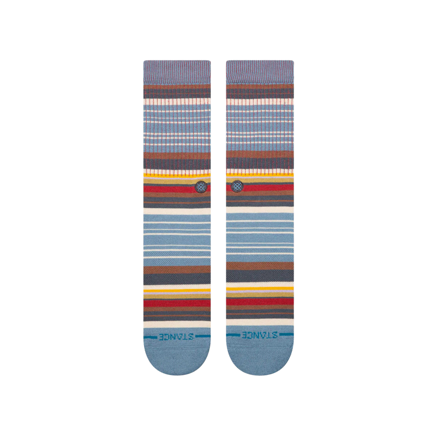 A pair of stance jorongo pop crew socks with a multicolor striped pattern featuring shades of blue, brown, red, yellow, and white, displayed against a plain white background.