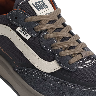 close up of a A low-top vans ultrarange se 2.0 sneaker against a solid white background. The shoe features a dark gray upper with a prominent off-white side stripe, a dark gray sole, and subtle orange-red accents on the collar lining and side details.