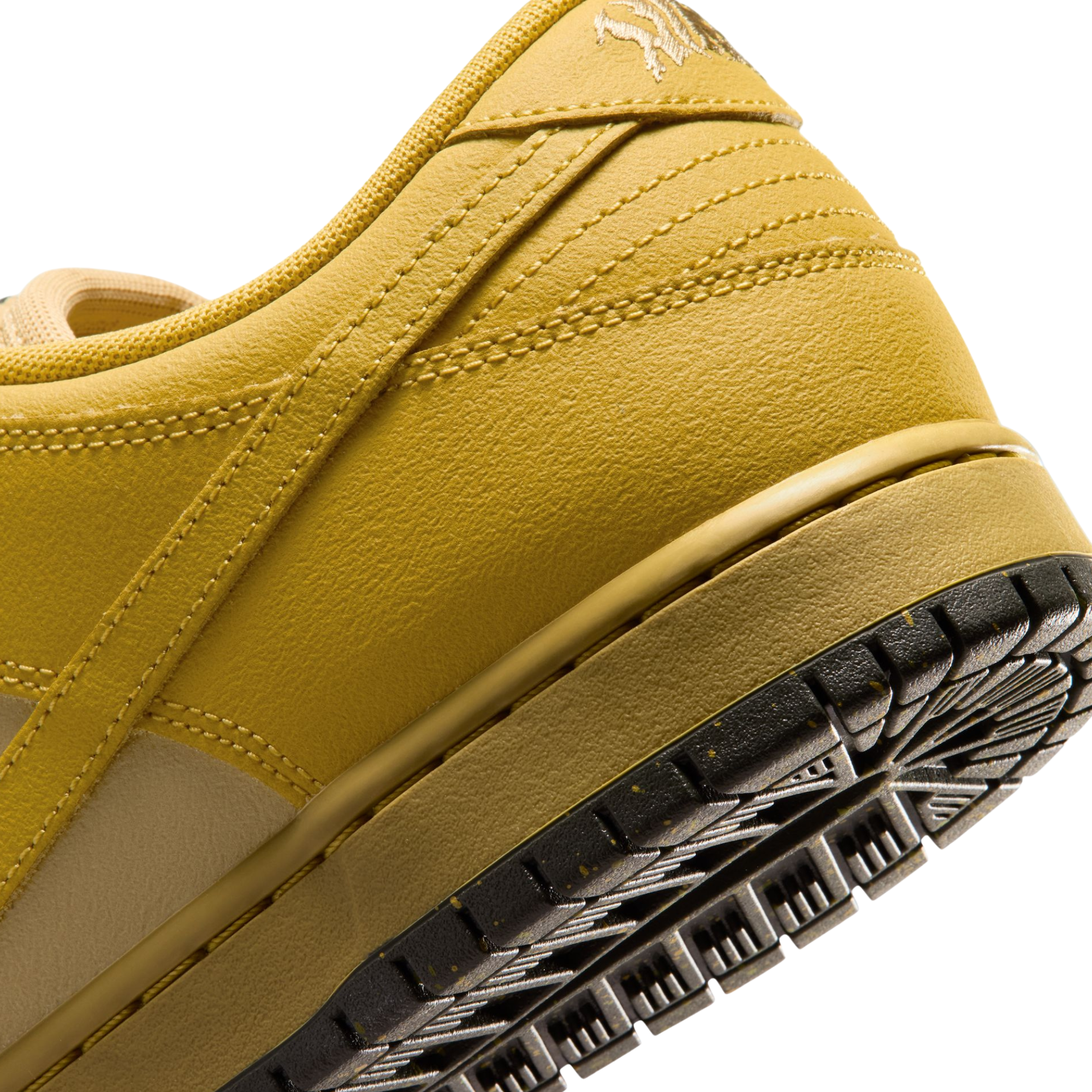 close up of A Nike SB Saffron Dunk Low sneaker in a yellow, tan, and sage green colorway, against a plain white background.