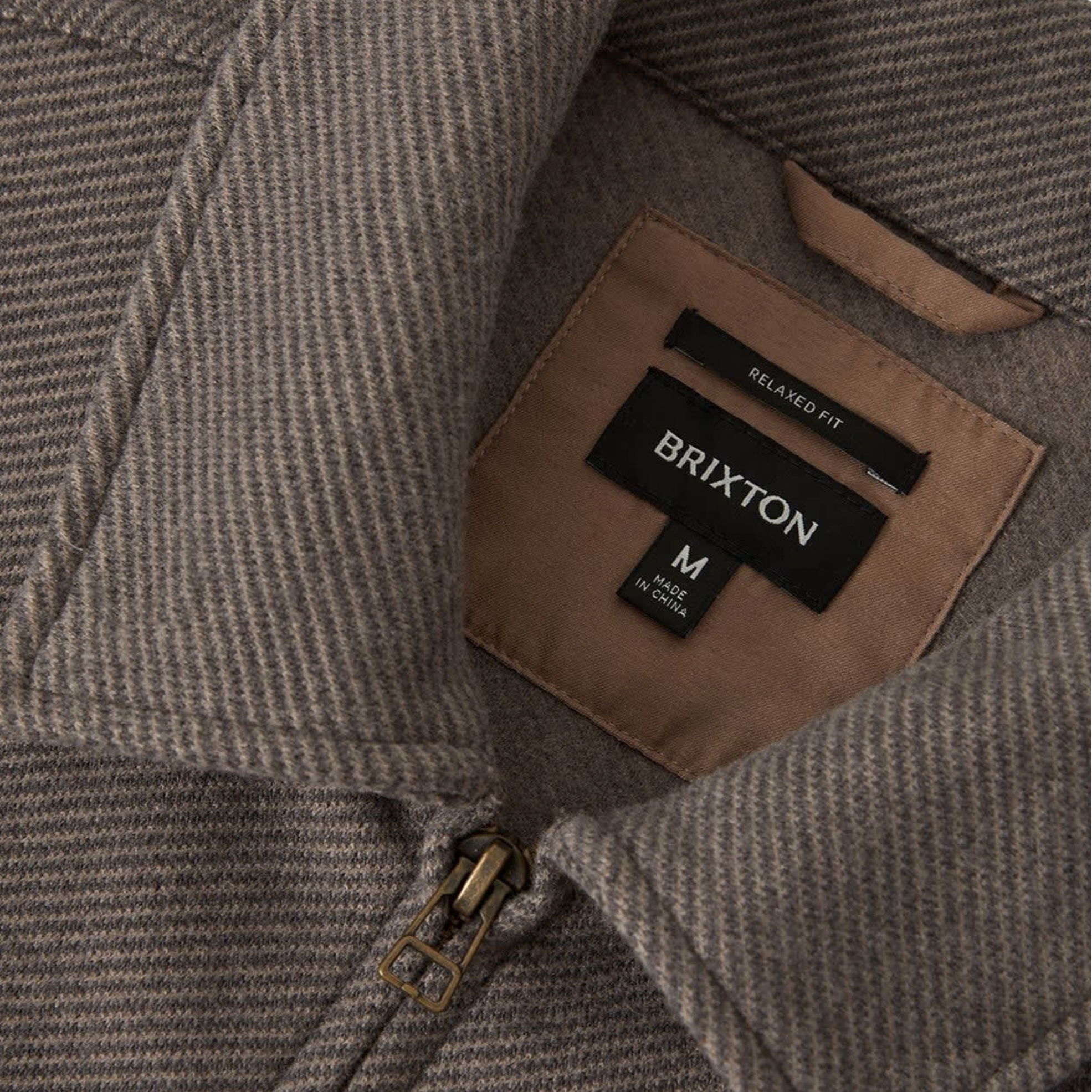 close up of a brown grey brixton trademark zip flannel jacket on a white background