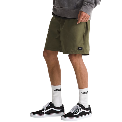 Person wearing green vans range sport shorts, white socks, and black sneakers on a white background