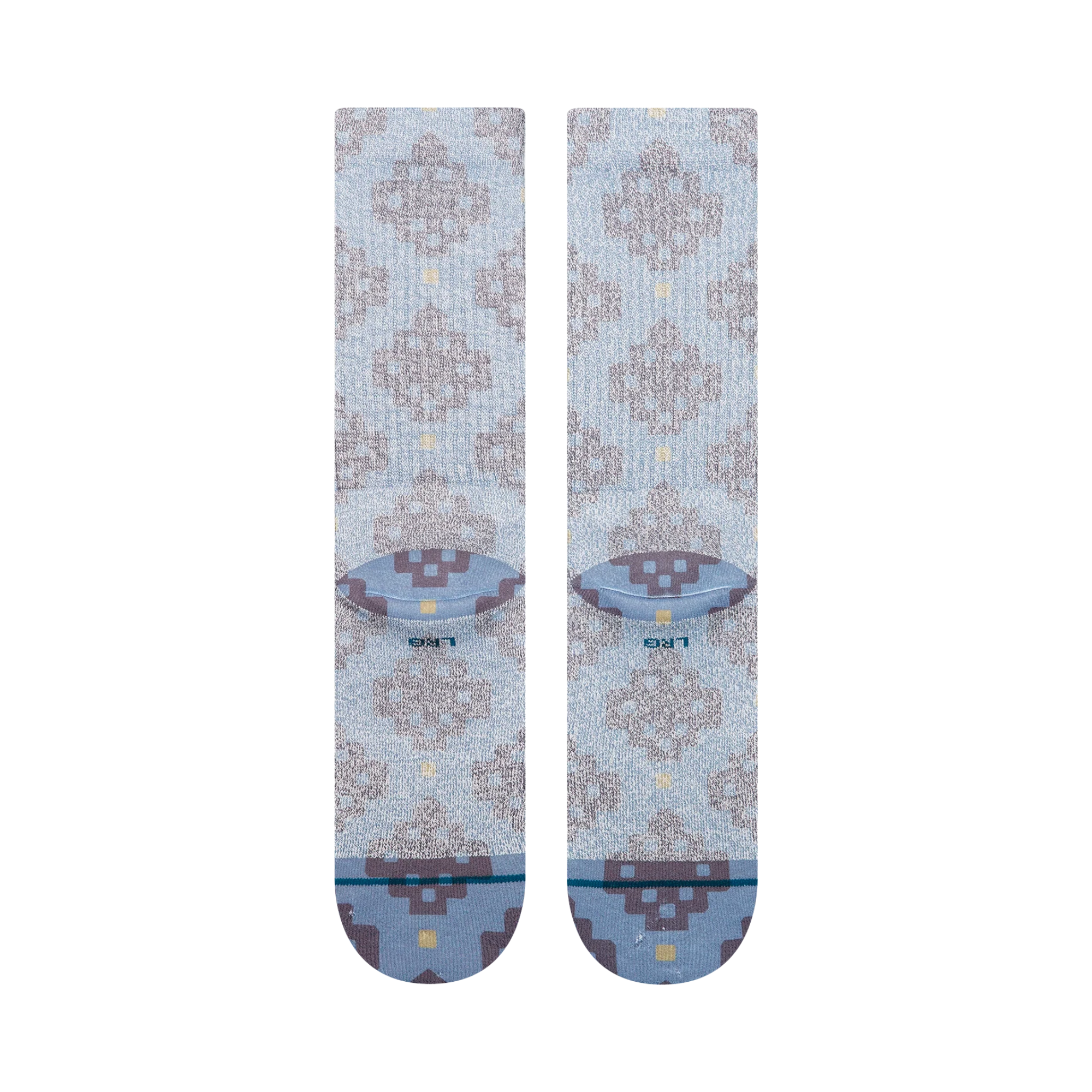 A pair of Stance alhambra butterblend crew socks in a light blue-gray colorway with a distressed brown tree pattern and small yellow accents, shown on a plain white background.