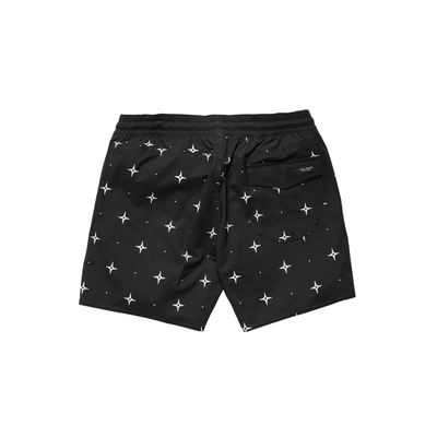 Man wearing black volcom lido swim shorts with star pattern on a white background