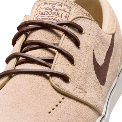 A Nike sb janoski low-top sneaker in a light beige suede and canvas mix, featuring a dark brown Swoosh logo, matching brown laces, and a thick white rubber sole.