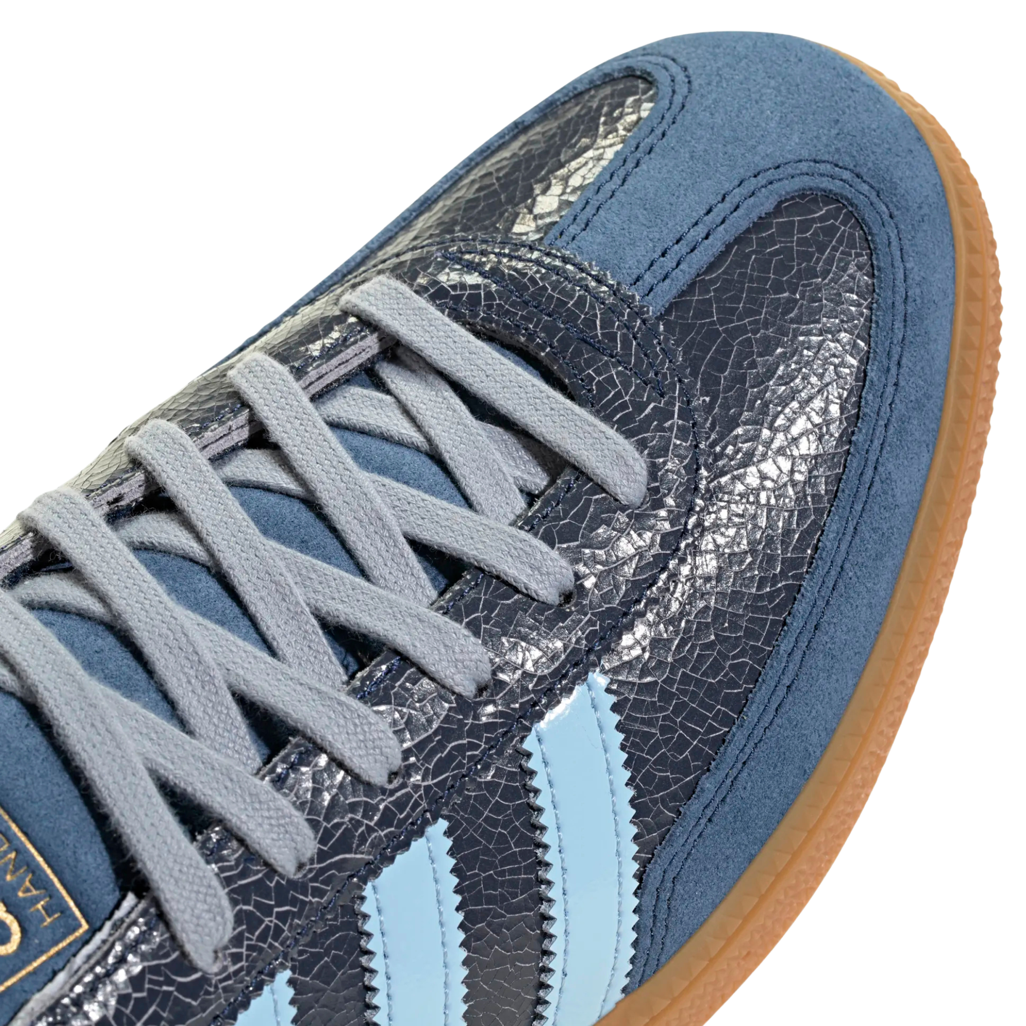 close up of A single Adidas handball spezial sneaker in navy blue suede and textured leather, featuring light blue stripes, a light blue heel tab, and a brown gum sole, shown against a plain white background.