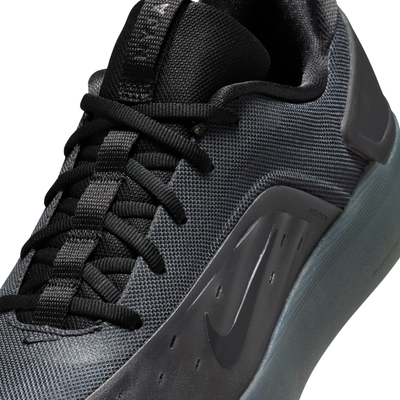 close up of A black Nike nyjah 4 skateboard sneaker with a textured synthetic upper, black laces, a black sole, and a small red pull tab on the heel, shown from a side profile against a white background.