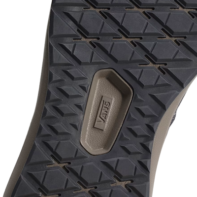 close up of a A low-top vans ultrarange se 2.0 sneaker against a solid white background. The shoe features a dark gray upper with a prominent off-white side stripe, a dark gray sole, and subtle orange-red accents on the collar lining and side details.