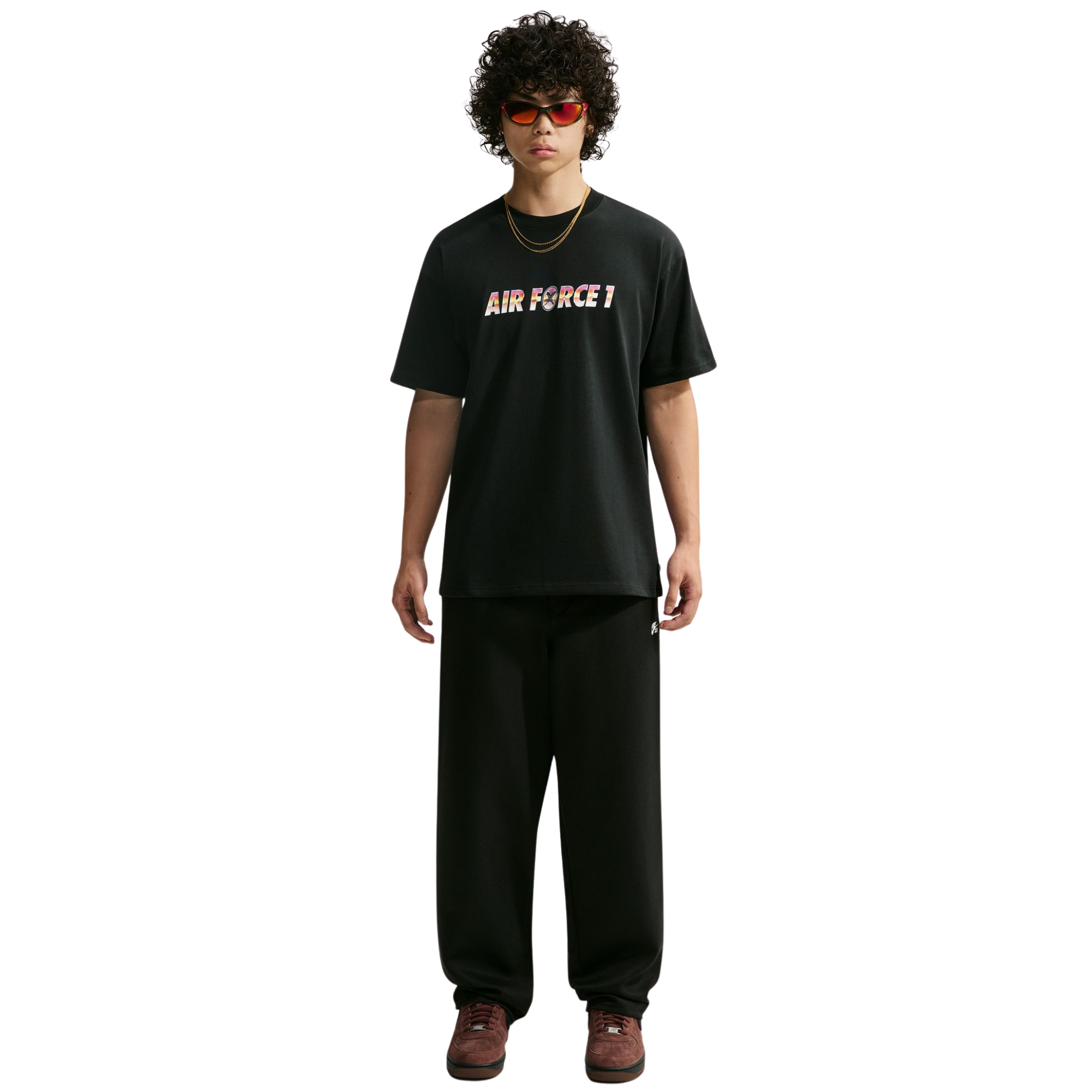 A model wearing a nike sb yuto horigome black t-shirt with 'AIR FORCE 1' printed across the chest in a colorful gradient pattern, paired with black sweatpants and brown shoes, shot against a solid white background.
