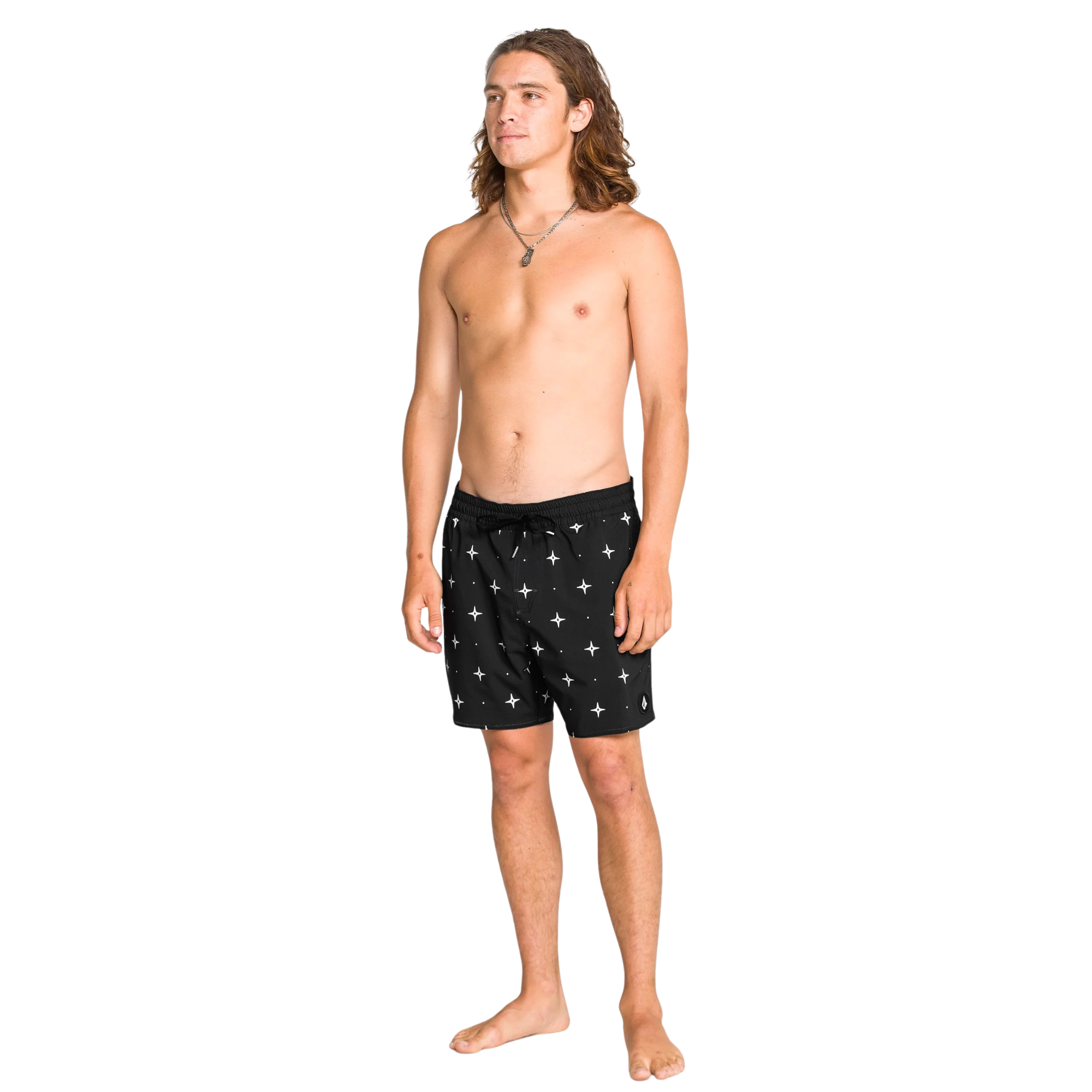 Man wearing black volcom lido swim shorts with star pattern on a white background
