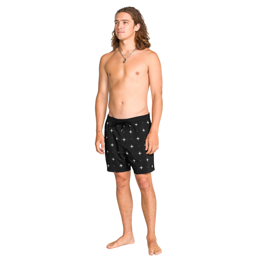 Man wearing black volcom lido swim shorts with star pattern on a white background