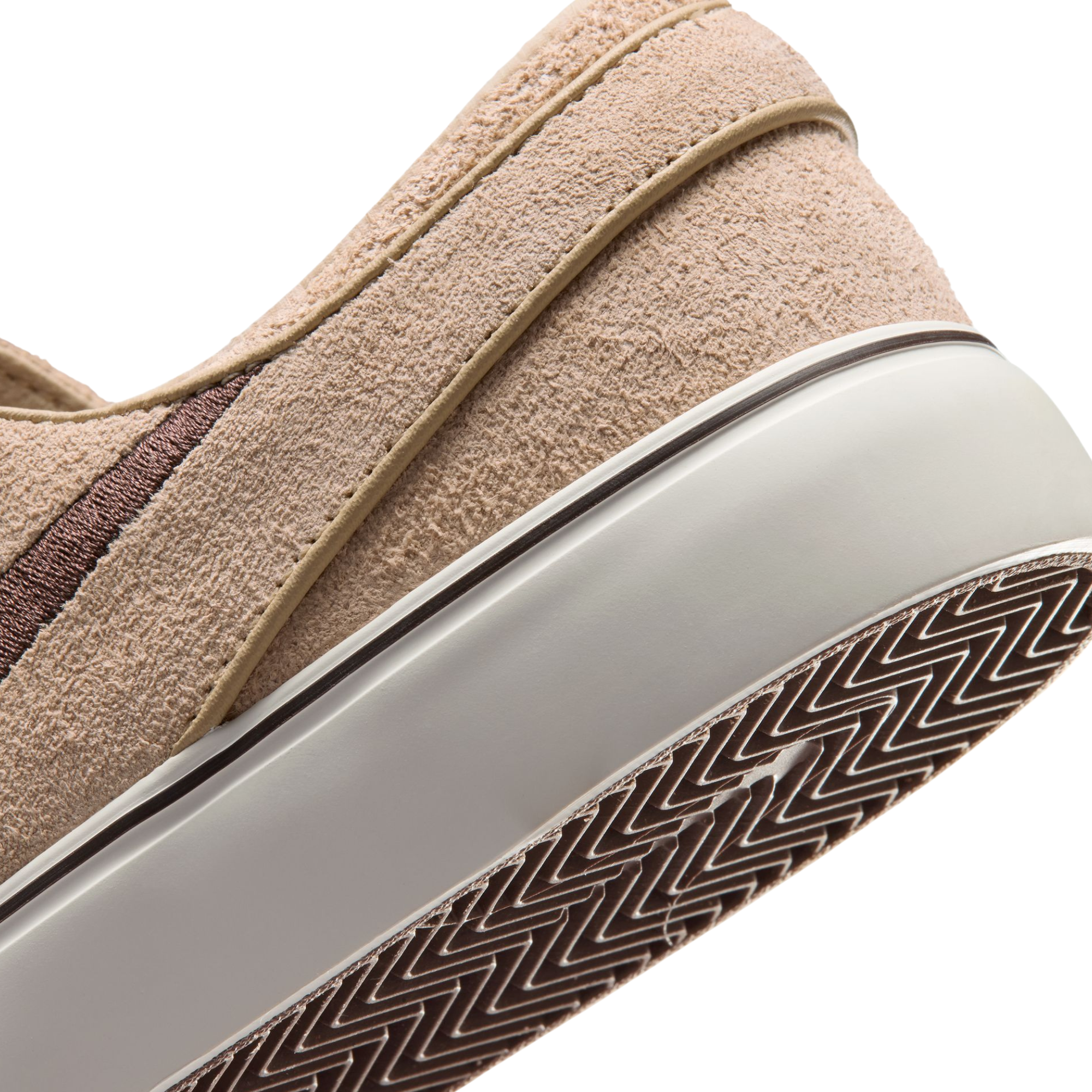 A Nike sb janoski low-top sneaker in a light beige suede and canvas mix, featuring a dark brown Swoosh logo, matching brown laces, and a thick white rubber sole.