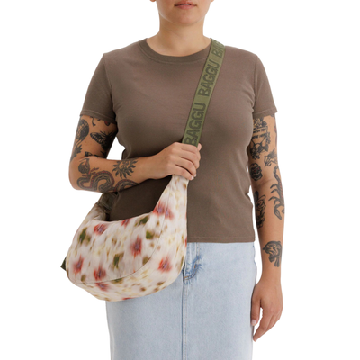 Person holding a floral-patterned bag with a visible brand logo on a white background
